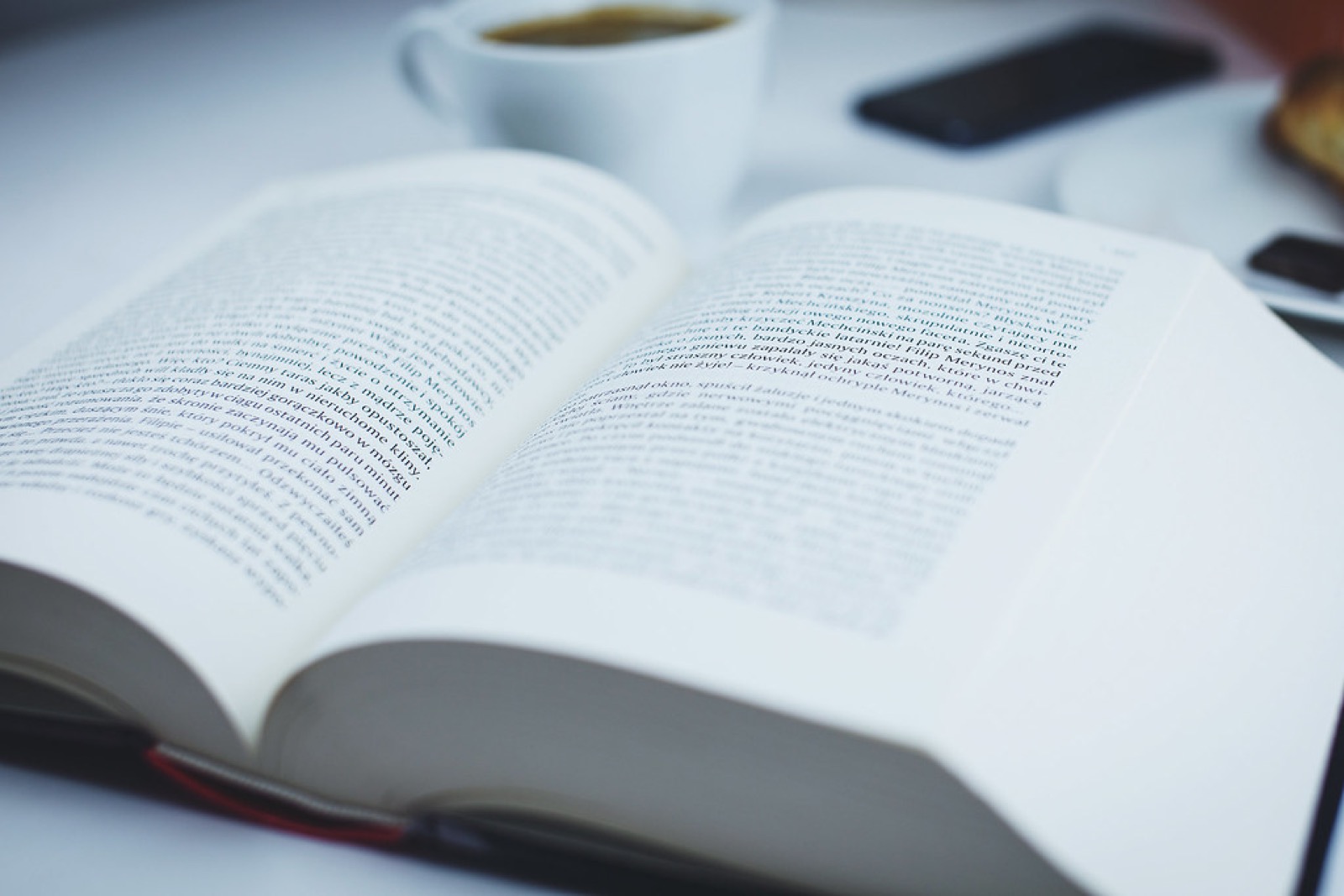 An open book beside a cup of coffee