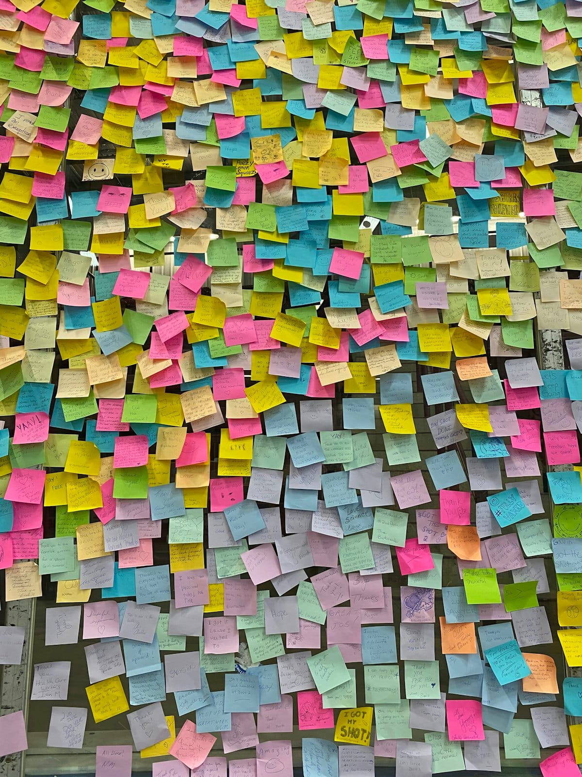 A wall densely covered in coloured sticky notes
