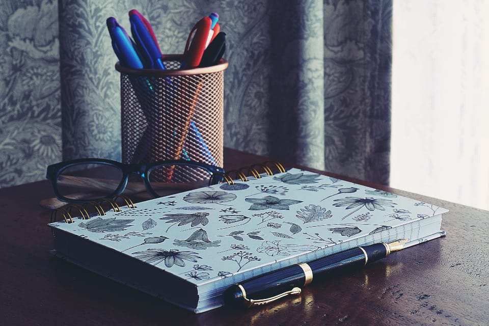 An open notebook beside books on a desk