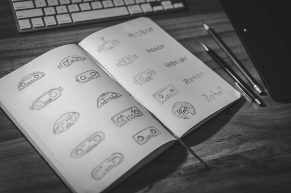 A notebook of hand-sketched icon variations beside a keyboard