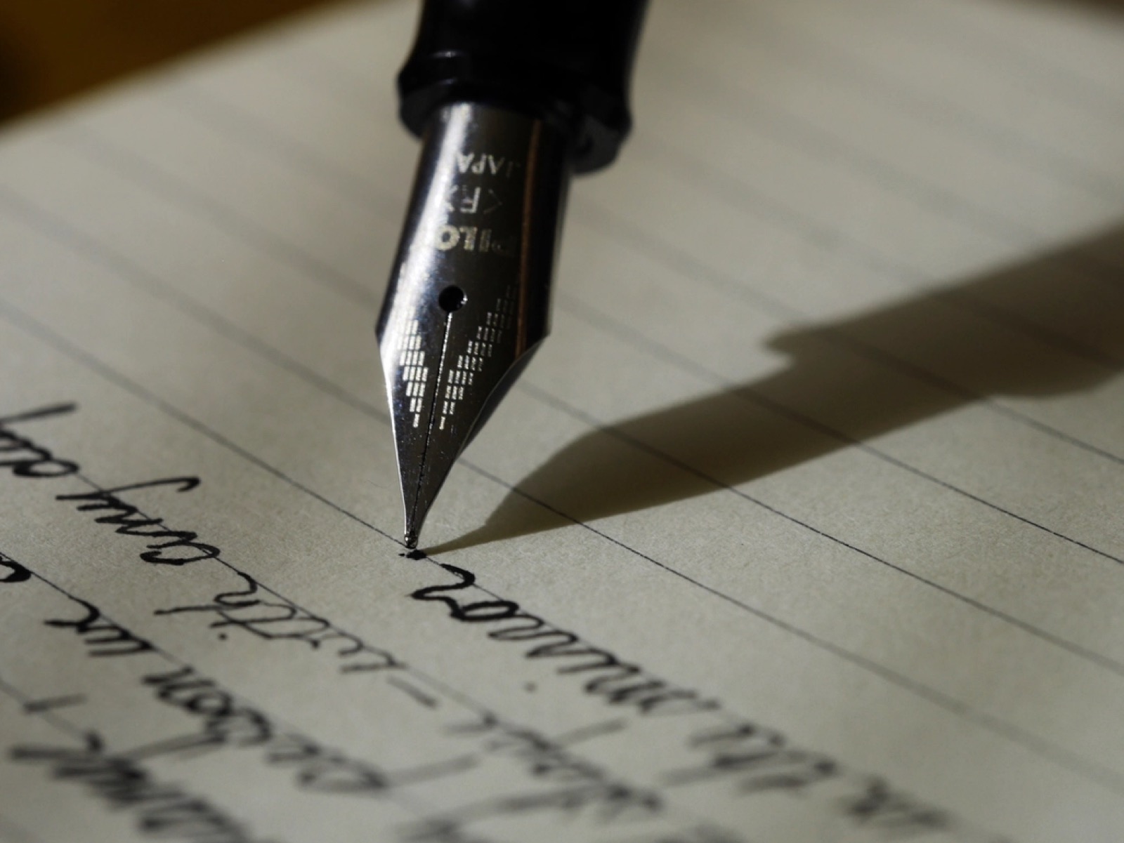 A fountain pen writing on lined paper