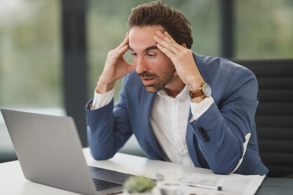 A man working at a laptop, looking tired