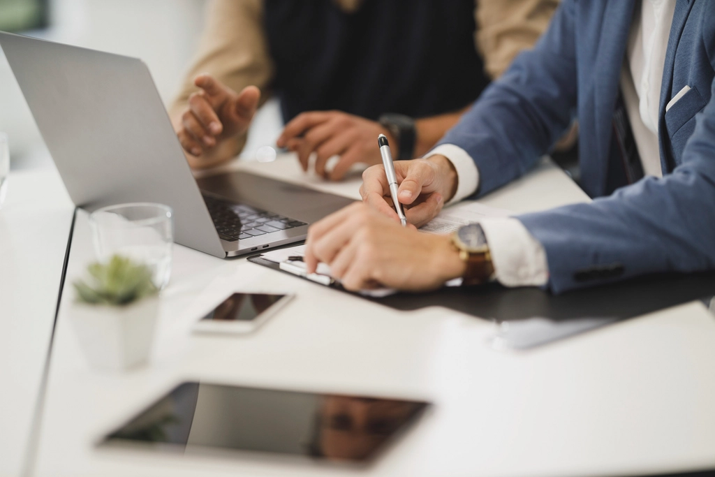 Two people's hands resting on a table during a meeting