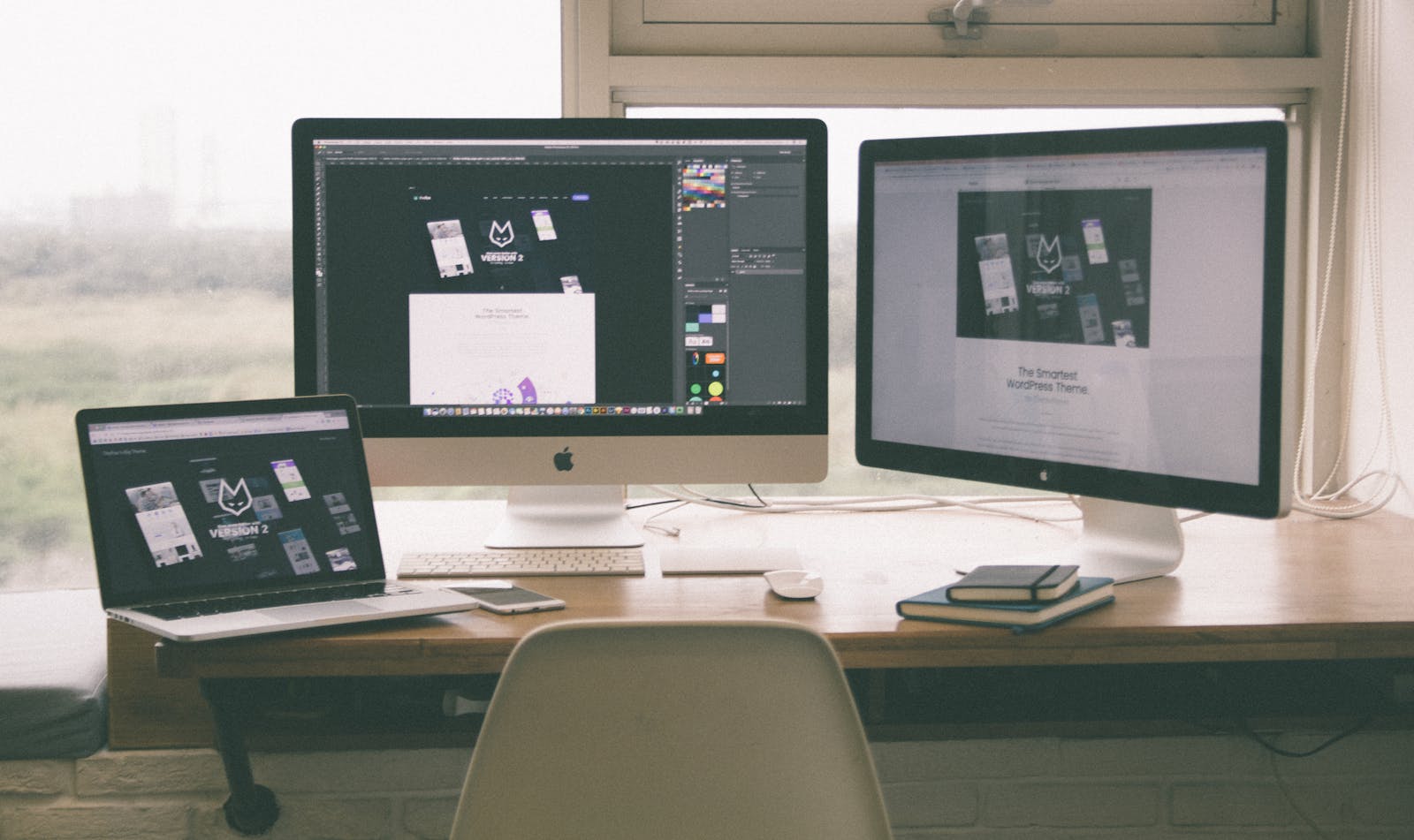 Desk with an iMac, Cinema Display and MacBook all showing the same WordPress theme website