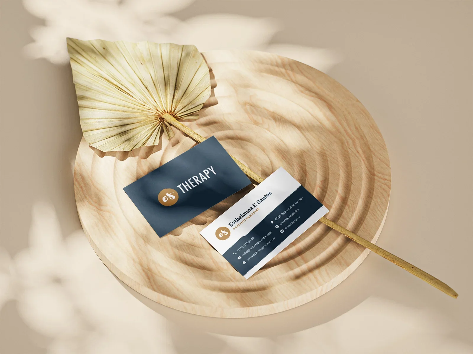 ES Therapy Centre business cards styled with a dried palm leaf